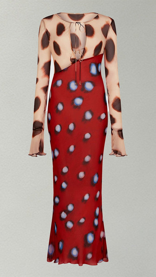 A long-sleeve midi dress with a split design: one half is beige with dark brown leopard spots, and the other half is red with blue and white spots, featuring a tie-front neckline.