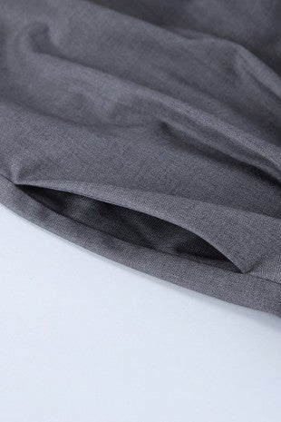 Close-up of a dark gray textured fabric draped over a white surface, showing the material's fine weave and soft folds.
