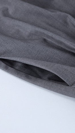 Close-up of a dark gray textured fabric draped over a white surface, showing the material's fine weave and soft folds.