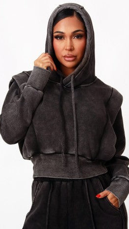 A woman wearing a dark gray washed cropped hoodie with drawstrings and a matching dark gray sweatpants, shown against a plain white background.