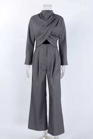 A dark gray two-piece outfit displayed on a mannequin, featuring a long-sleeve draped wrap-style top with a crossover front and matching high-waisted wide-leg trousers.