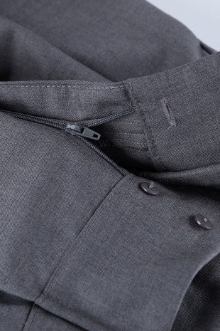 Close-up detail of a dark gray textured fabric garment, showing a zipper, button, and stitched fold.