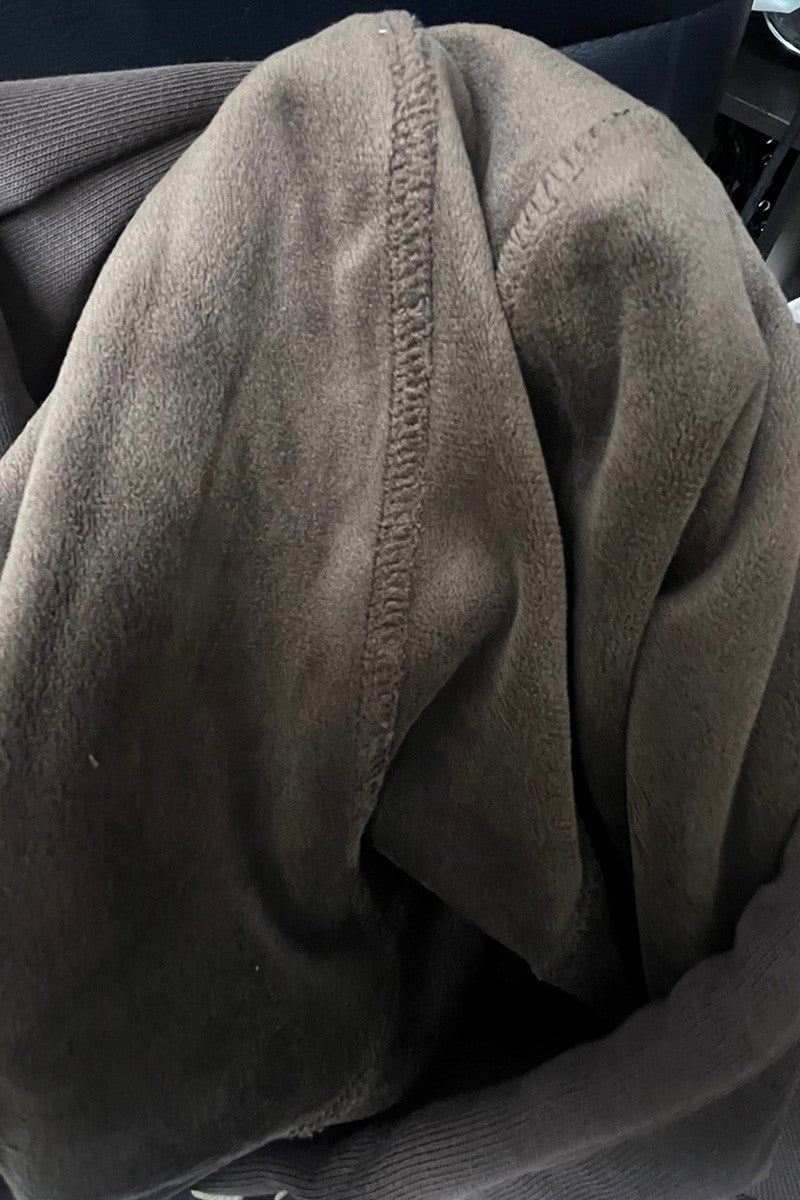 A close-up of fleece-lined hood or jacket, showing the soft textured fabric and a central seam, set against a dark background.